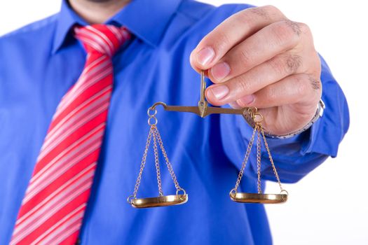 Businessman with red tie and blue shirt holding golden scales on balance, isolated on white background.