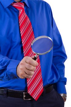 Businessman with red tie and blue shirt holding magnifying glass and examining, isolated on white background.