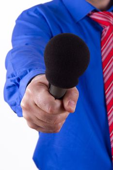 Businessman with red tie and blue shirt holding and giving microphone for interview, isolated on white background.