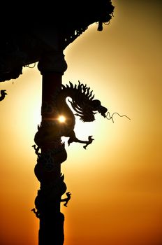 Dragon roll column statue silhouette with sunset background, Dragon eating the sun concept