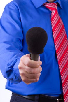 Businessman with red tie and blue shirt holding and giving microphone for interview, isolated on white background.