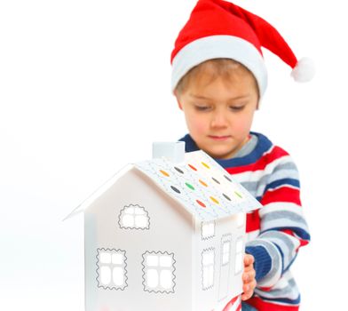 Christmas theme - Smiling boy in Santa's hat with white gingerbread house, isolated on white
