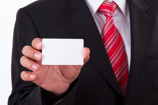 Businessman in dark suit and white shirt with red striped tie, shows white blank business card with space.