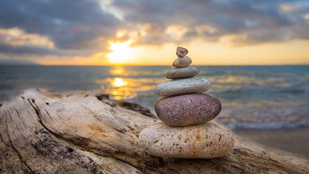 Zen Stones on a tree trunk and sunset in the background.
