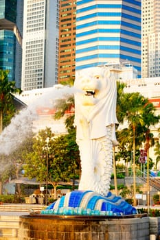 Singapore, Republic of Singapore -  March 08, 2013: The Merlion fountain spouts water in front of the Singapore downtown. Merlion is a creature with a lion head, often seen as a symbol of Singapore
