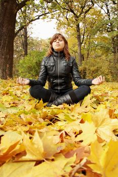 young woman meditates in the autumn park