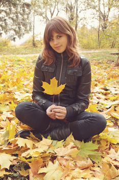 Portrait of a girl sitting on the autumn leaves