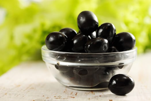 Black olives in a bowl transparent and lettuce