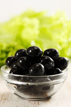 Black olives in a bowl transparent and lettuce