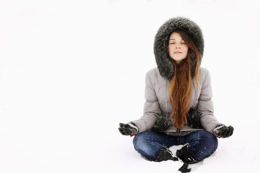 Young girl in lotus pose in the snow