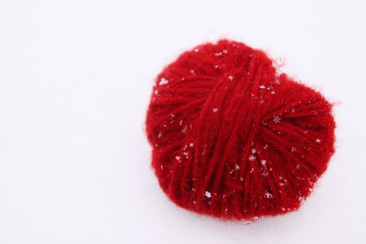 heart of red woolen threads in the snow