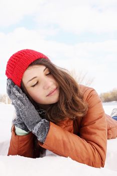 Beautiful young woman lying in the snow