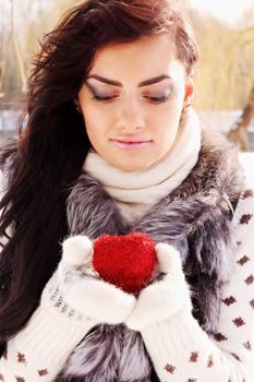 Young woman holding a red heart in the hands of