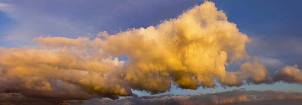 Cumulus Clouds against Blue Sky at Sunset Panorama