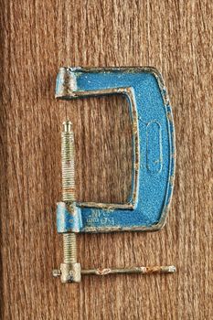 An old and rusty clamp over wooden background