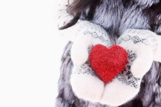 hands in woolen mittens holding red heart