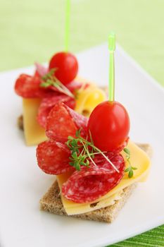 Canapes with cheese, salami, tomatoes and lettuce Cres