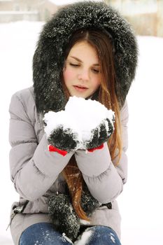 A young woman holding a bunch of snow