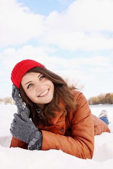 Beautiful young woman lying in the snow