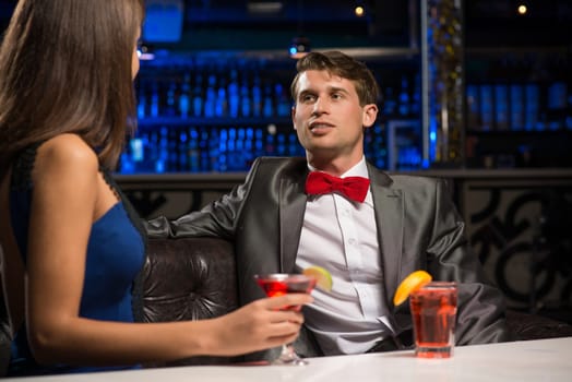 portrait of a man in a nightclub, sitting on the couch and talking with woman