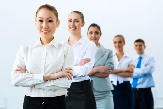 group of business people standing in a row, smiling and crossing his arms