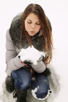 Young girl blowing on snow in their hands