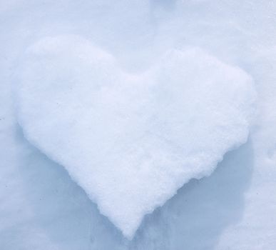 White icy heart on the background of snow