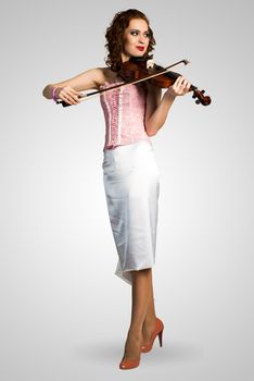 young attractive woman in pink corset playing the violin, enjoys music