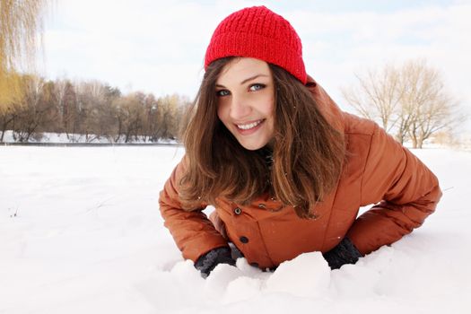 Beautiful young woman lying in the snow