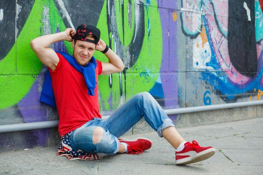 Happy teens boy sitting near painted wall and having fun