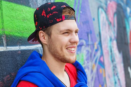 Portrait of happy teens boy sitting near painted wall and having fun