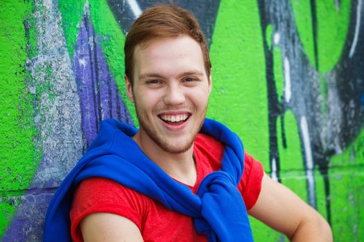 Portrait of happy teens boy sitting near painted wall and having fun