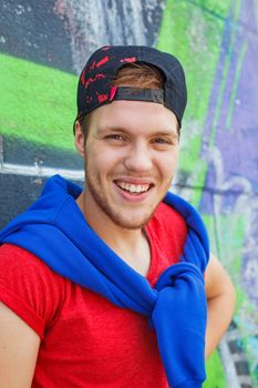 Portrait of happy teens boy sitting near painted wall and having fun