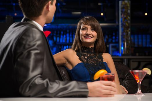 portrait of a woman in a nightclub, sitting on the couch and talking with man