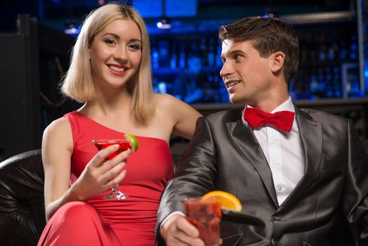 couple in a nightclub on the couch with a drink, have fun