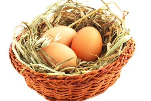 Three eggs in basket with the hay against the white background