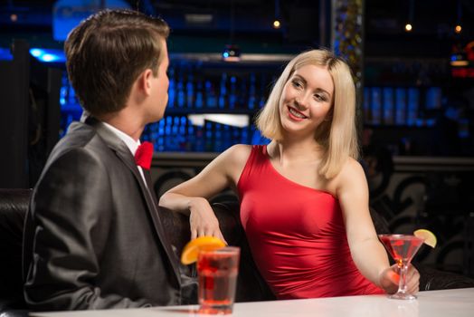 portrait of a woman in a nightclub, sitting on the couch and talking with man