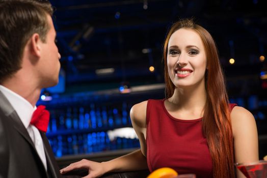 portrait of a woman in a nightclub, sitting on the couch and talking with man