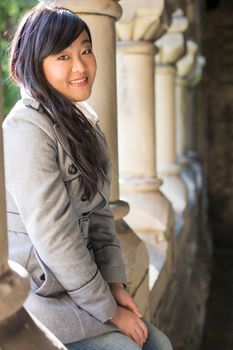 Young woman sitting next to a row of stone pillars