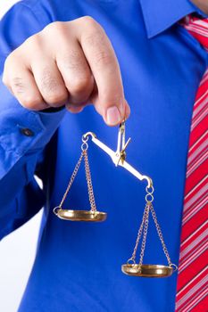 Businessman with red tie and blue shirt holding golden scales unbalanced, isolated on white background.