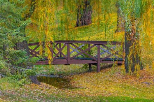 Autumn - Small bridge colorfull foliage reflection in the water