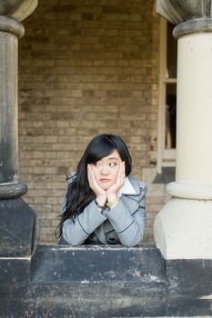 Young woman leaning forward next to stone pillars