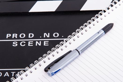Black cinema clapper board and notebook for scenario with pen, isolated on white background.