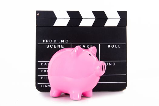 Black cinema clapper board with pink piggy bank, isolated on white background.