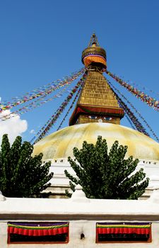 bodhnath stupa in kathmandu with buddha eyes and prayer flags on clear blue sky background