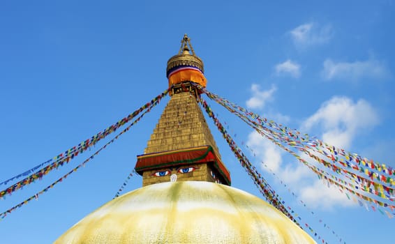 bodhnath stupa in kathmandu with buddha eyes and prayer flags on clear blue sky background