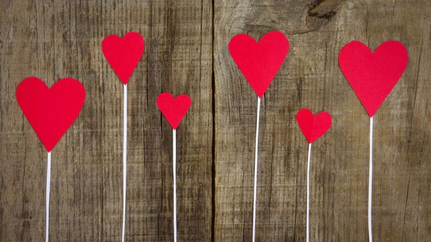 Several Red Hearts on wooden textured background.