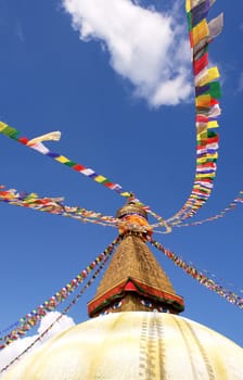 bodhnath stupa in kathmandu with buddha eyes and prayer flags on clear blue sky background