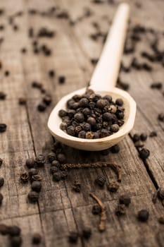 A spoon full of Peppercorn on wood background