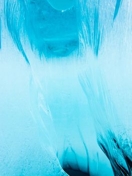 Underwater crevasse in thick layer of ice floating on blue lake
